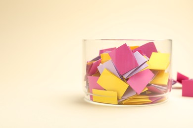 Photo of Jar with colorful pieces of paper on beige background, closeup. Space for text