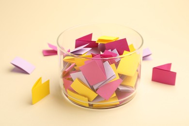 Photo of Jar with colorful pieces of paper on beige background, closeup