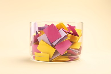 Photo of Jar with colorful pieces of paper on beige background, closeup