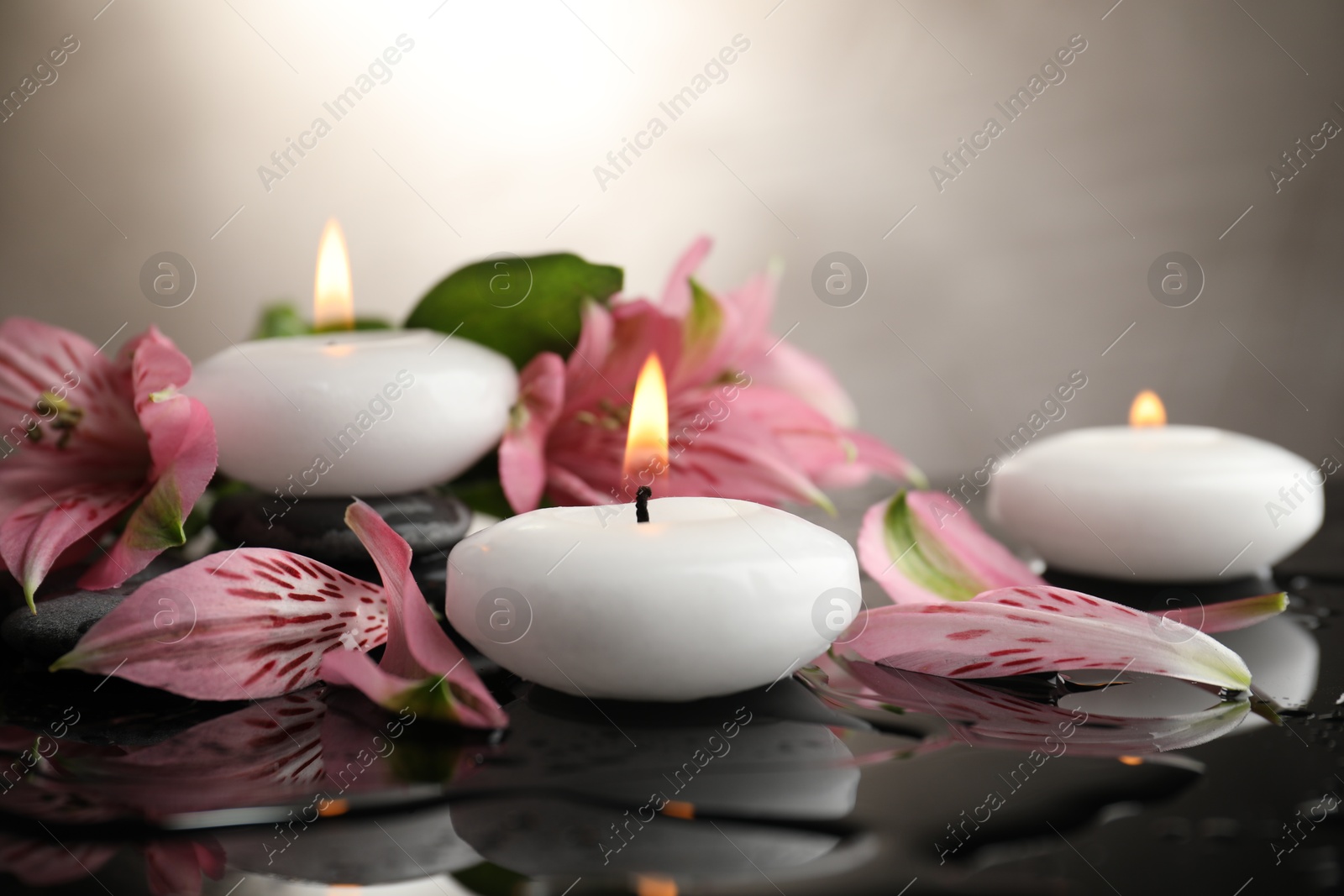 Burning candles and beautiful flowers on wet black table, closeup. Space for text Photo of Burning candles and beautiful flowers on wet black table, closeup. Space for text