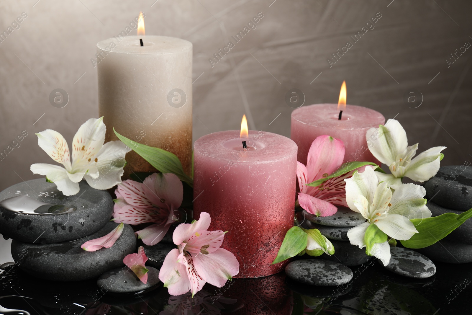 Burning candles, spa stones and beautiful flowers on wet black table, closeup Photo of Burning candles, spa stones and beautiful flowers on wet black table, closeup