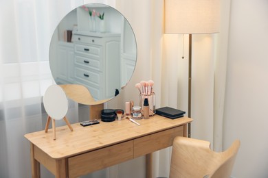 Photo of Different makeup products and brushes on vanity indoors