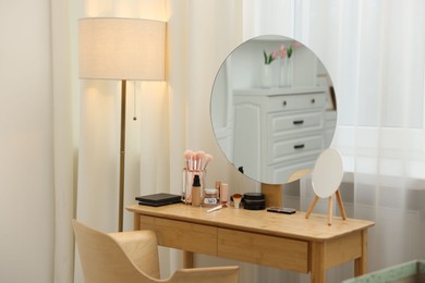 Photo of Different makeup products and brushes on vanity indoors