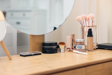 Photo of Different makeup products and brushes on vanity indoors, closeup