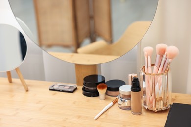 Photo of Different makeup products and brushes on vanity indoors, closeup