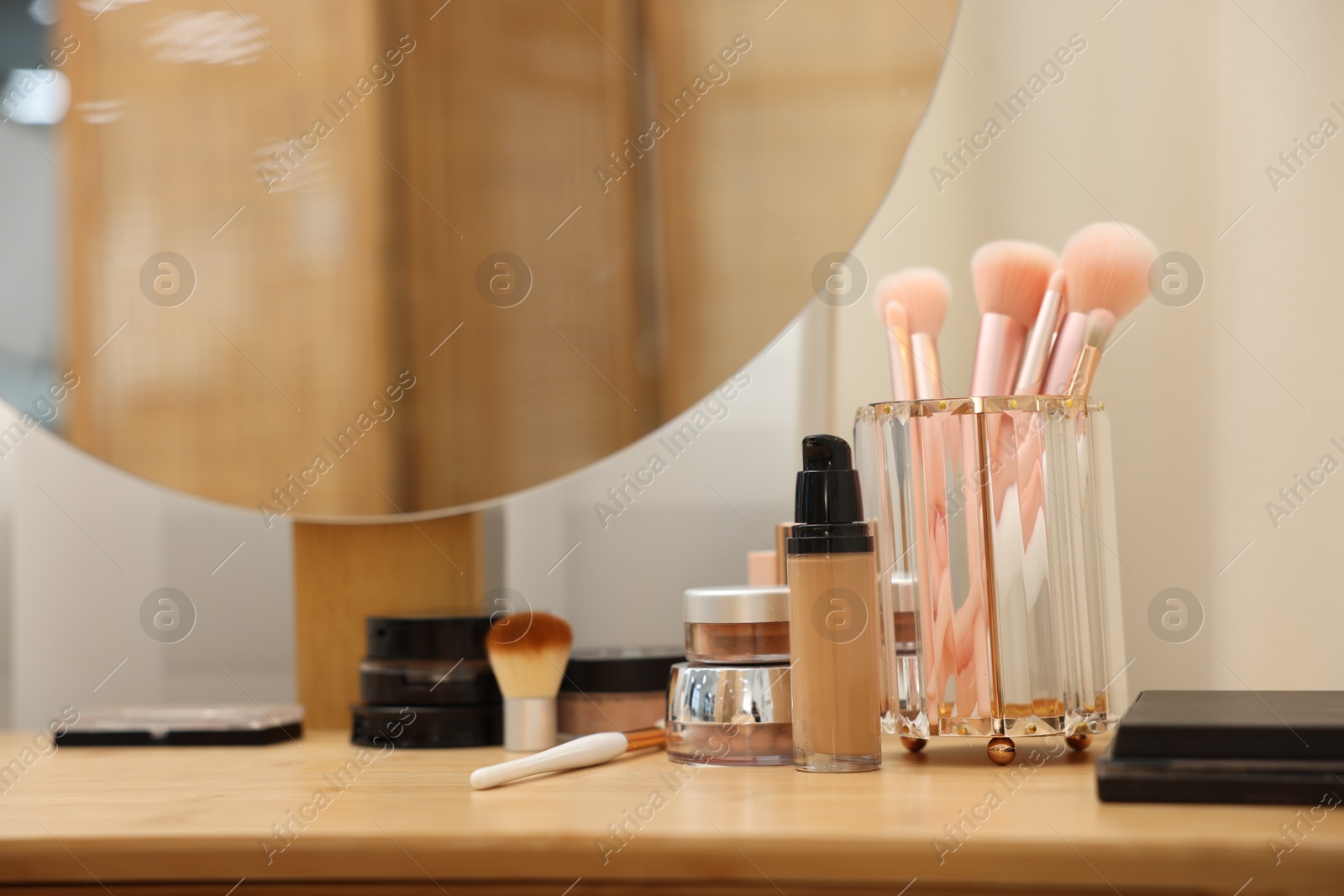Different makeup products and brushes on vanity indoors, closeup Photo of Different makeup products and brushes on vanity indoors, closeup