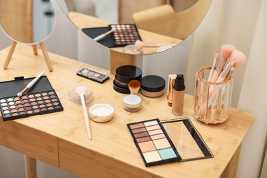 Photo of Different makeup products and brushes on vanity indoors, closeup