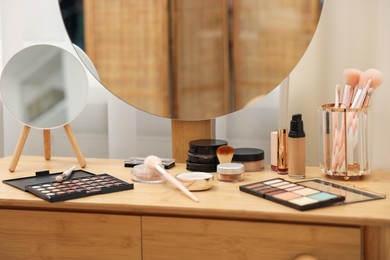 Photo of Different makeup products and brushes on vanity indoors, closeup
