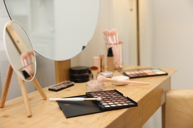 Photo of Different makeup products and brushes on vanity indoors, closeup