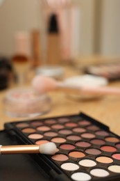 Photo of Eyeshadow palette and brush on wooden table, closeup