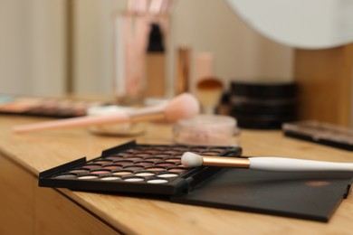 Photo of Eyeshadow palette and brush on wooden table, closeup