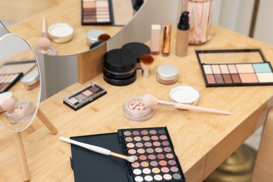 Photo of Different makeup products and brushes on vanity indoors, closeup
