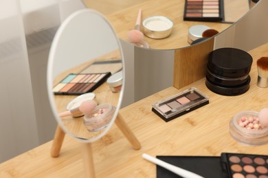 Photo of Different makeup products and mirror on vanity indoors, closeup