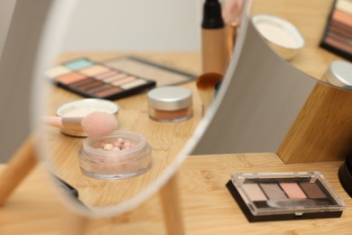 Photo of Different makeup products and mirror on vanity indoors, closeup