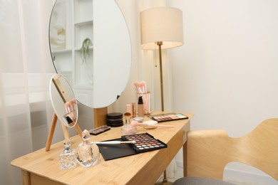 Photo of Different makeup products and brushes on vanity indoors