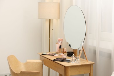 Photo of Different makeup products and brushes on vanity indoors