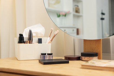 Photo of Different makeup products and brushes on vanity indoors, closeup