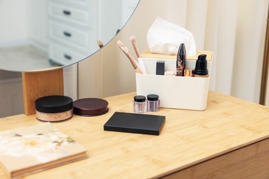 Photo of Different makeup products and brushes on vanity indoors, closeup