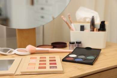 Photo of Different makeup products and brushes on vanity indoors, closeup