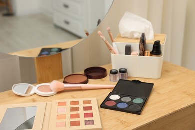 Photo of Different makeup products and brushes on vanity indoors, closeup