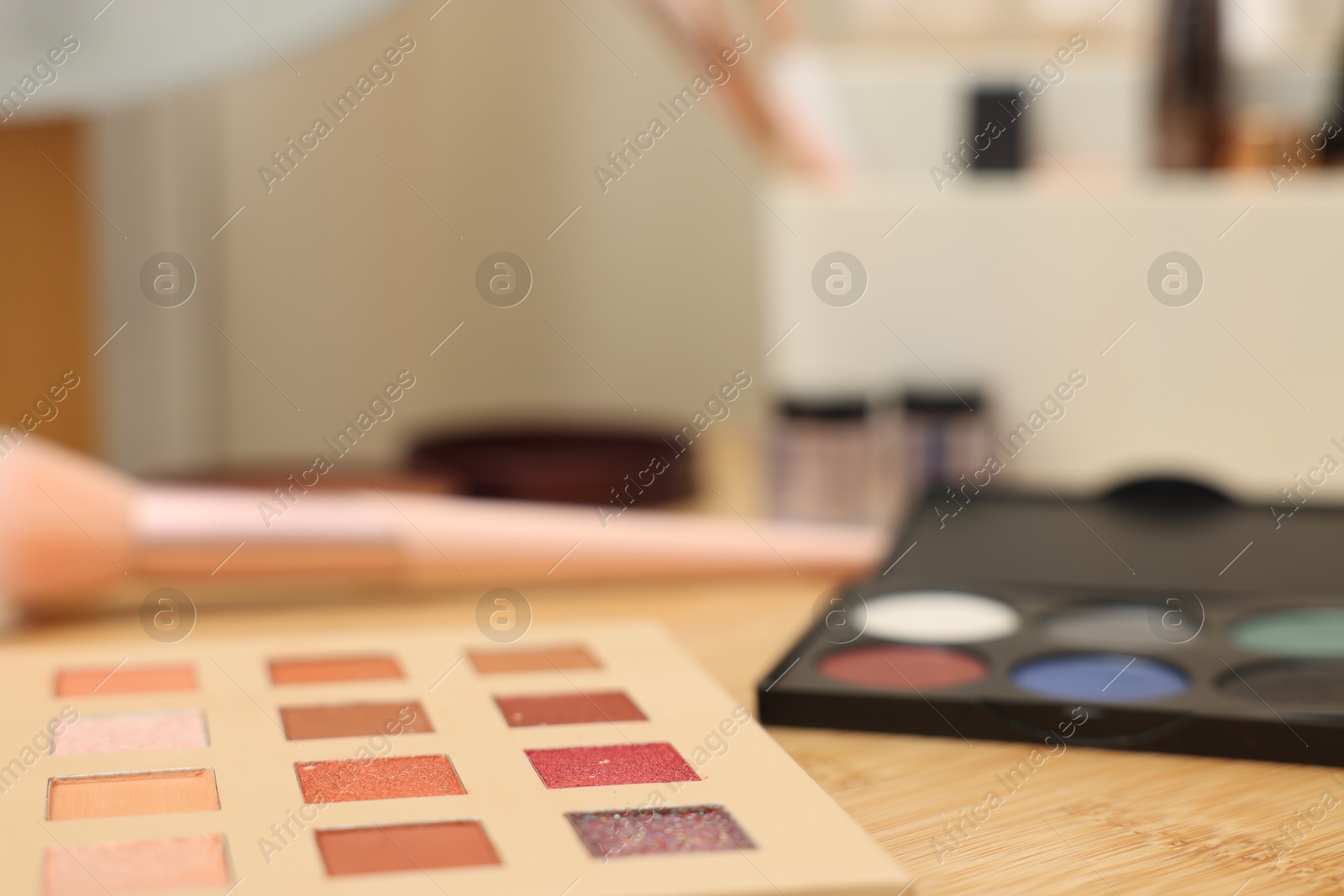 Eyeshadow palettes and brush on wooden table, closeup. Space for text Photo of Eyeshadow palettes and brush on wooden table, closeup. Space for text