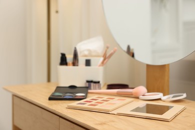 Photo of Different makeup products and brushes on vanity indoors, closeup