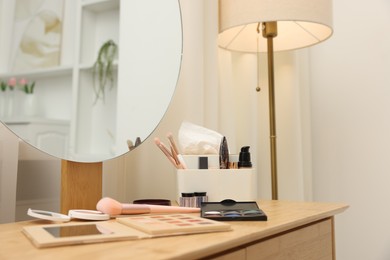 Photo of Different makeup products and brushes on vanity indoors, closeup