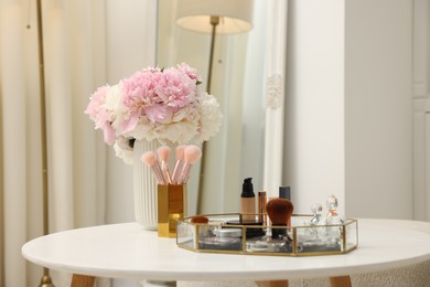 Photo of Tray with different makeup products on white table indoors. Space for text