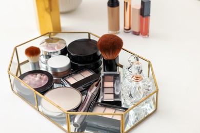 Photo of Tray with different makeup products on white table, closeup