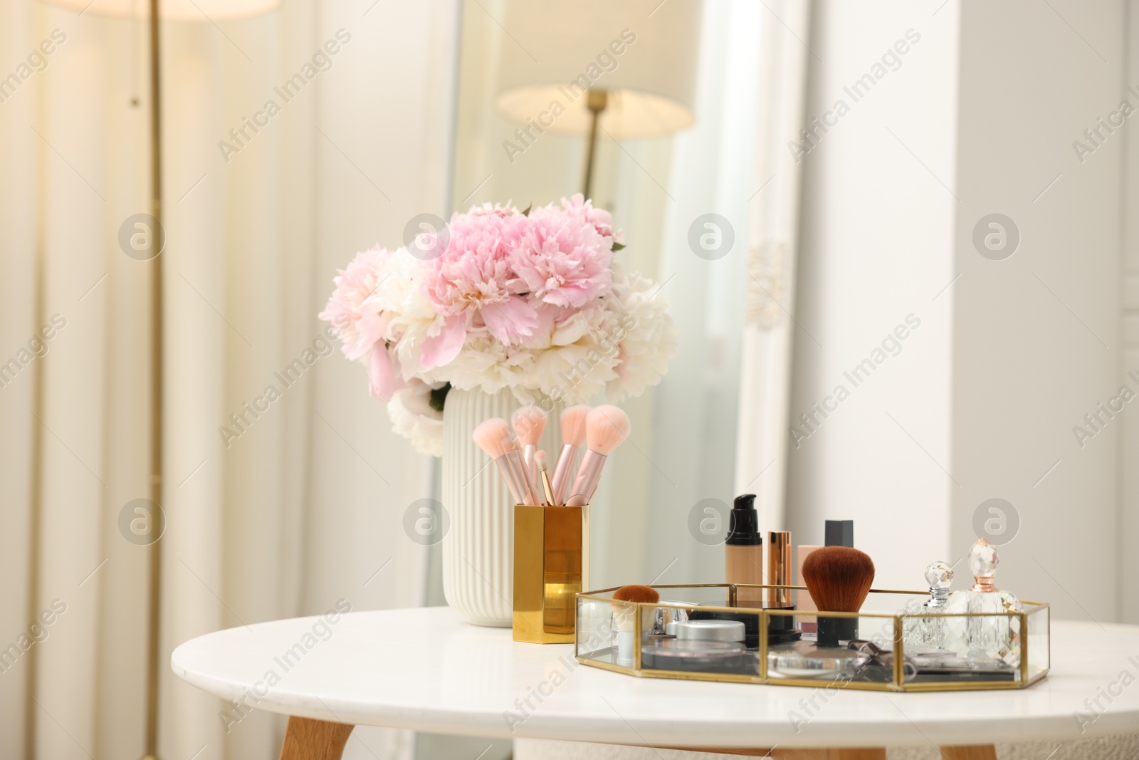 Tray with different makeup products on white table indoors Photo of Tray with different makeup products on white table indoors