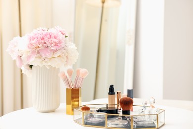 Photo of Tray with different makeup products on white table indoors. Space for text
