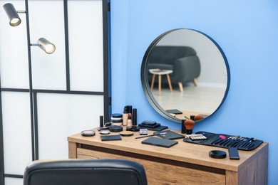 Photo of Different makeup products and brushes on vanity indoors
