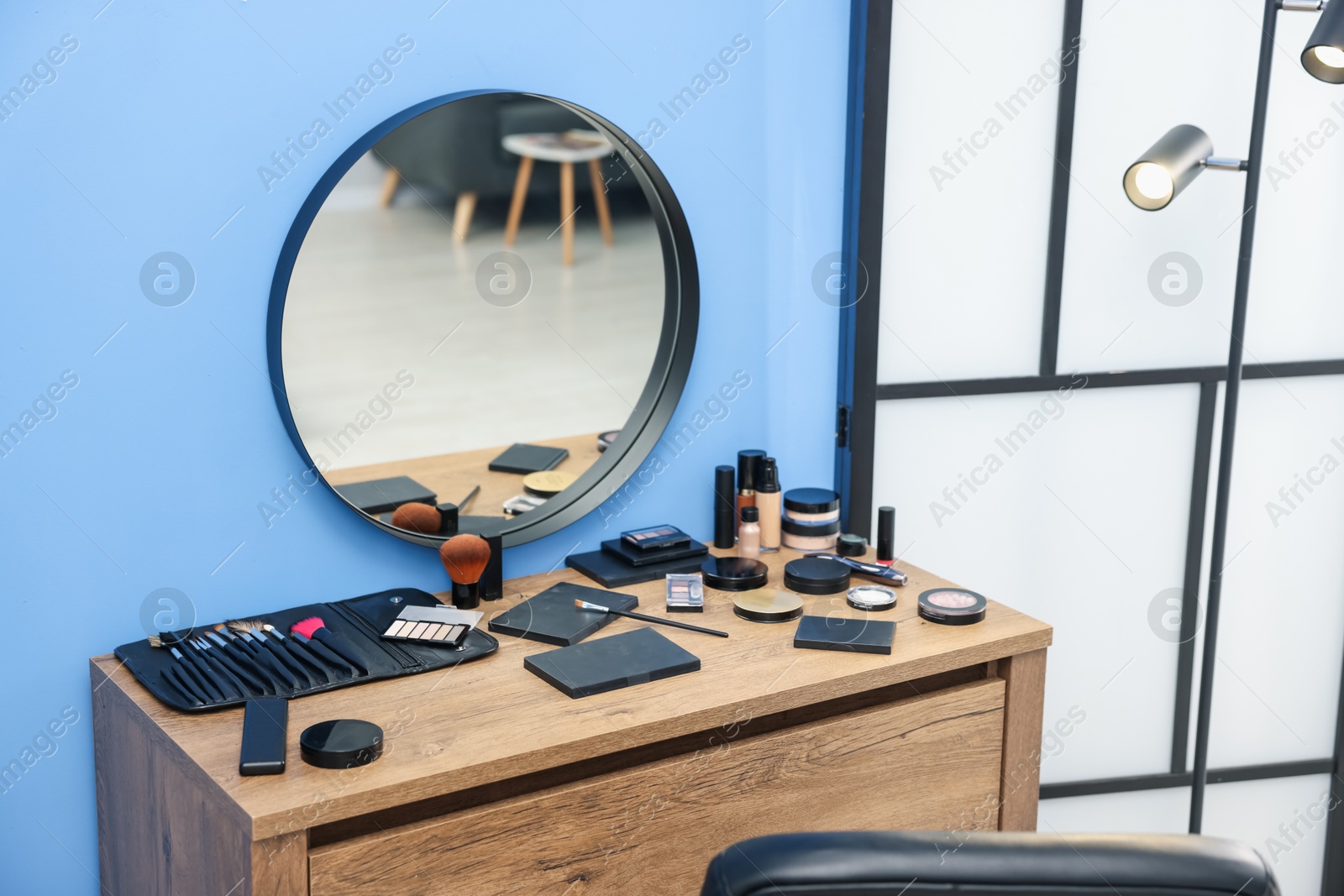 Different makeup products and brushes on vanity indoors Photo of Different makeup products and brushes on vanity indoors