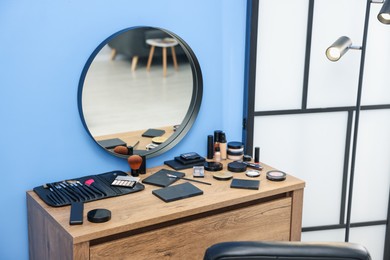 Photo of Different makeup products and brushes on vanity indoors