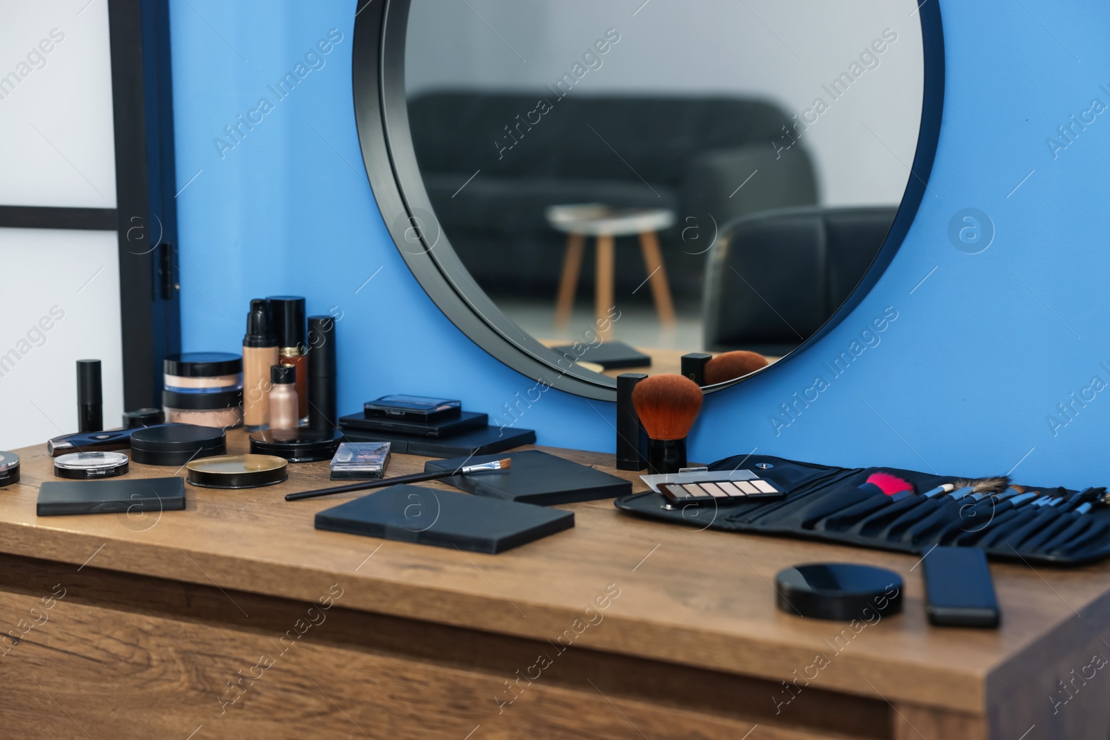 Photo of Different makeup products and brushes on vanity indoors, closeup