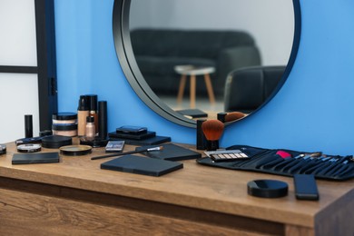 Photo of Different makeup products and brushes on vanity indoors, closeup