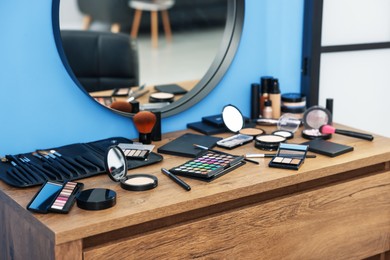 Photo of Different makeup products and brushes on vanity indoors, closeup