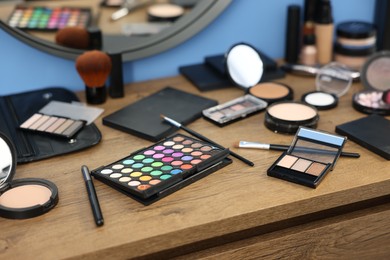 Photo of Different makeup products on wooden table indoors, closeup