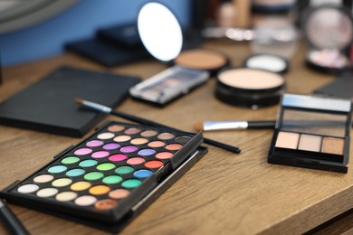 Photo of Different makeup products on wooden table indoors, closeup