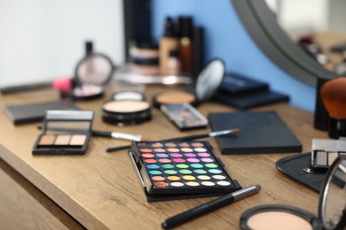 Photo of Different makeup products on wooden table indoors, closeup