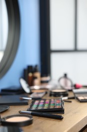 Photo of Different makeup products on wooden table indoors, closeup. Space for text