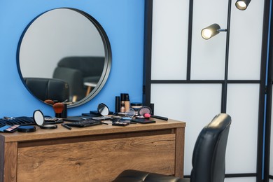 Photo of Different makeup products and brushes on vanity indoors
