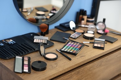 Photo of Different makeup products and brushes on vanity indoors, closeup