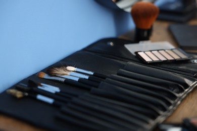 Photo of Makeup brushes and products on wooden table indoors, closeup. Space for text