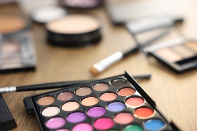 Photo of Different makeup products on wooden table, closeup