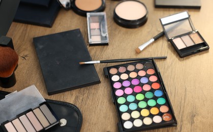 Photo of Different makeup products on wooden table, closeup