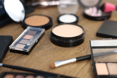 Photo of Different makeup products on wooden table, closeup