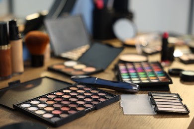 Photo of Different makeup products on wooden table indoors, closeup