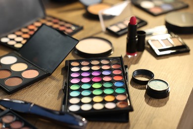 Photo of Different makeup products on wooden table, closeup