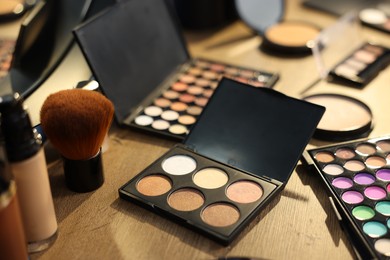 Photo of Different makeup products on wooden table, closeup